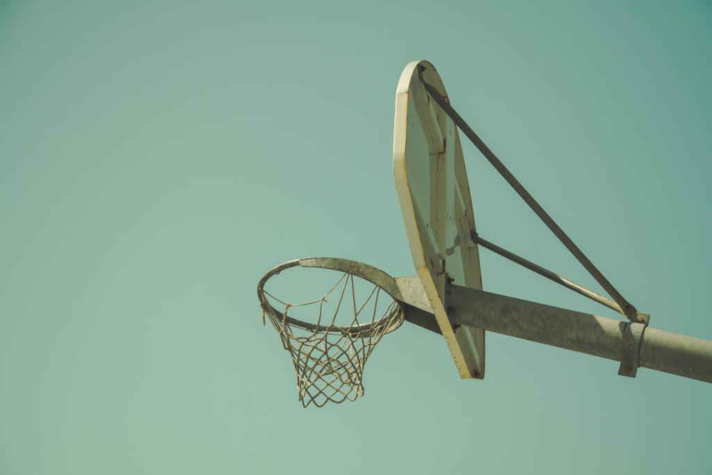 Old basketball hoop tattered net backboard against retro filter sky