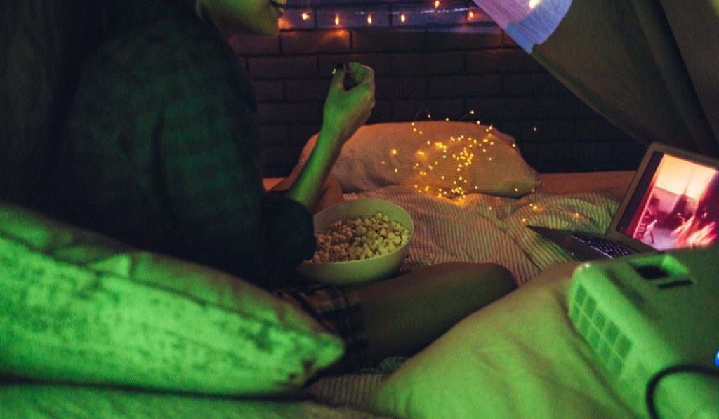 a girl with a bowl of popcorn watching a movie