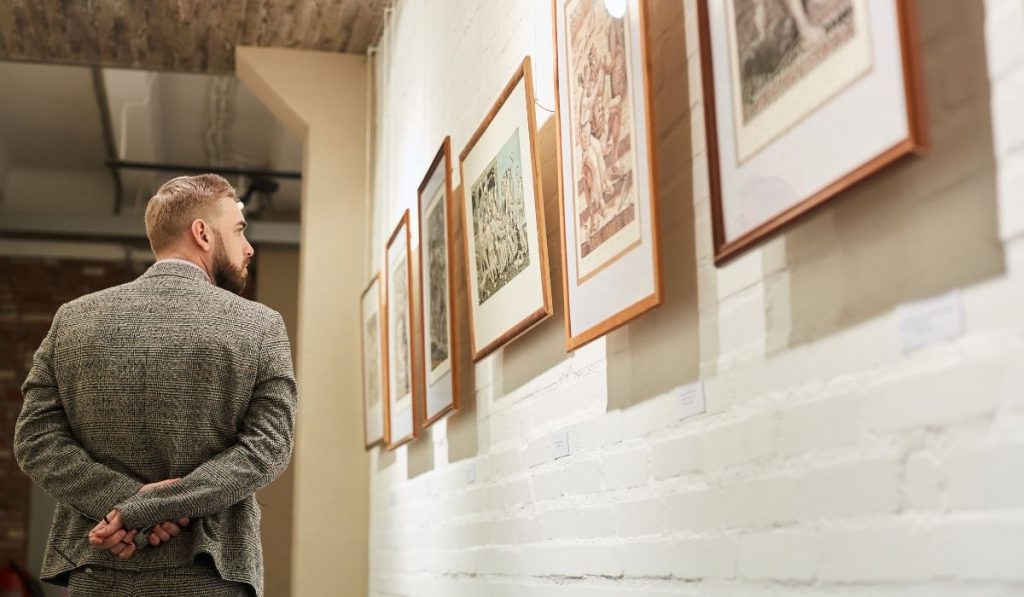 man looking at artwork pieces in an art gallery