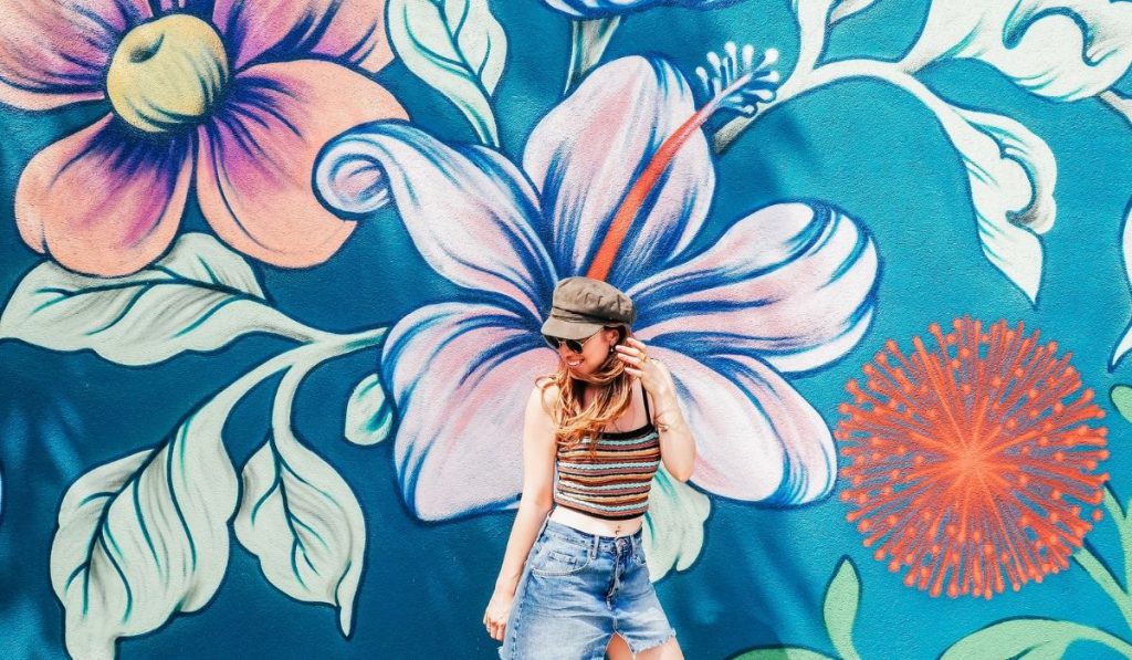 a girl posing behind a mural artwork of different flowers